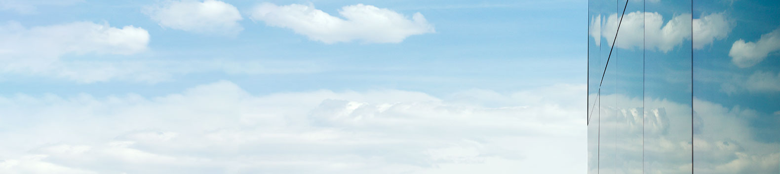 Blue sky with clouds and the side of a glass skyscraper