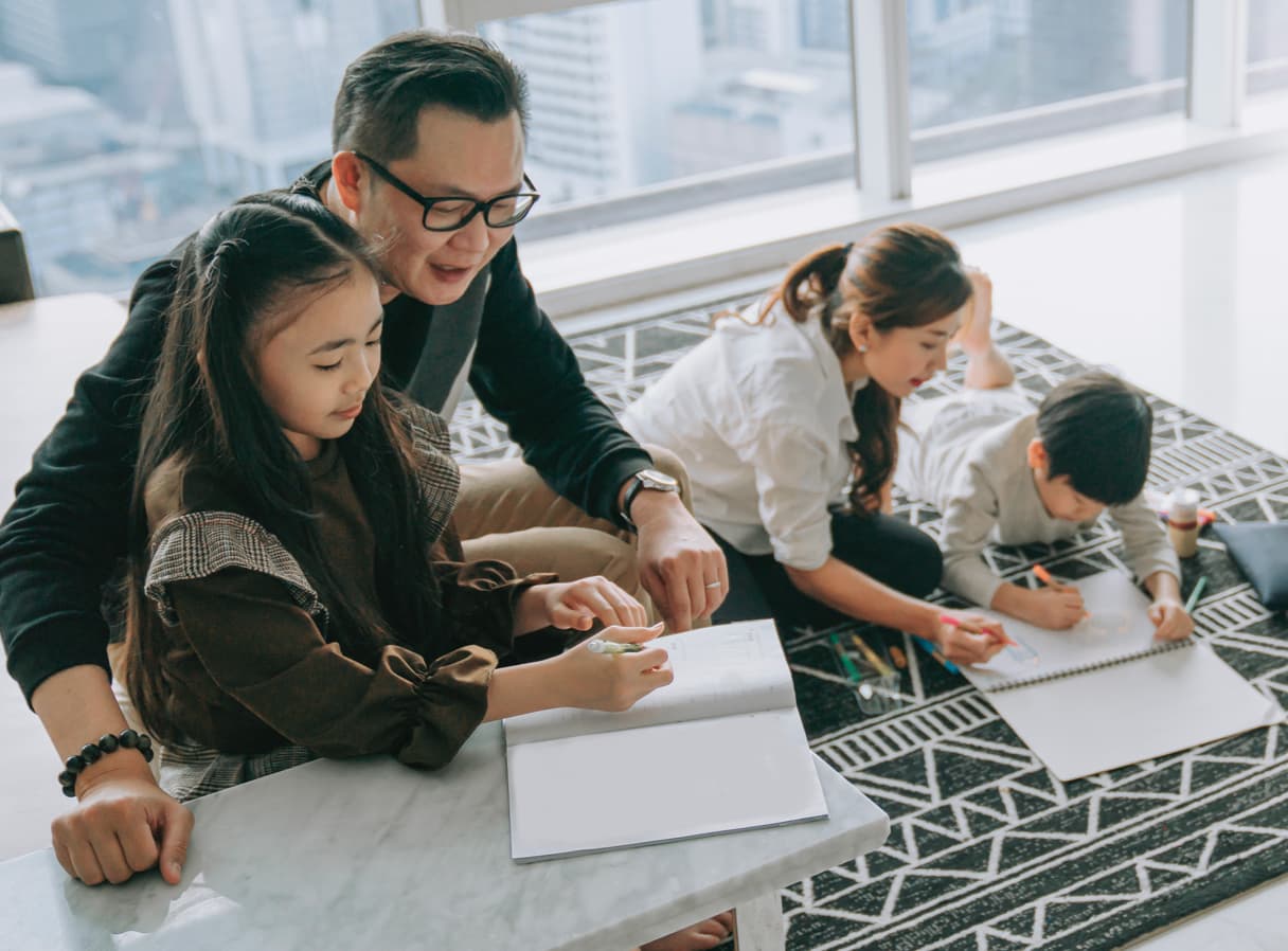 Family sitting together in a room drawing on paper.