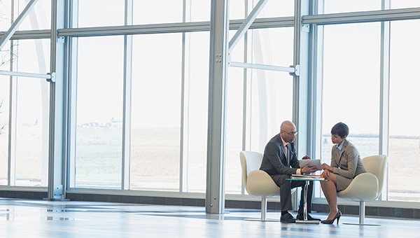 Businessman and woman sitting at a small table near windows