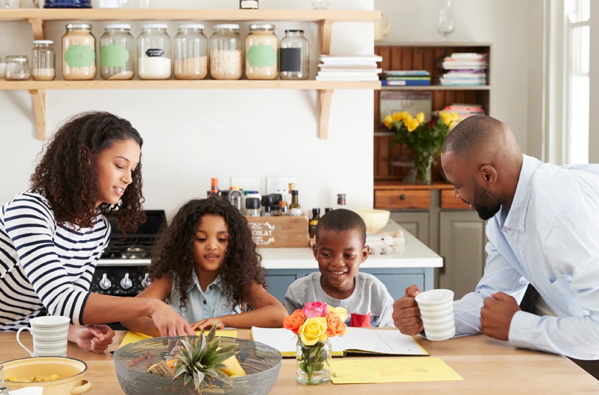 A family of four sitting at a kitchen table together  