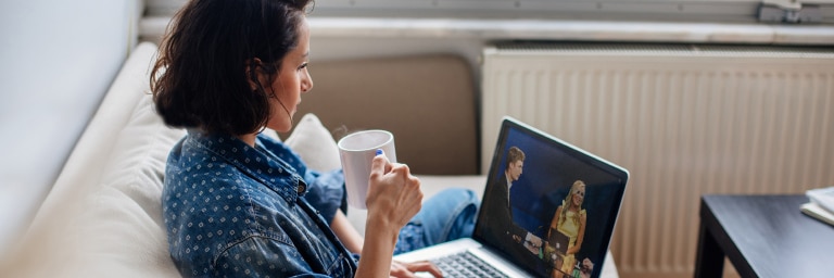 An investor looks at her laptop from her couch