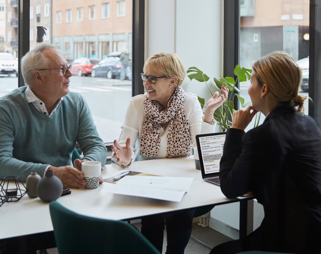 A couple sits across the table from a woman, having a conversation.