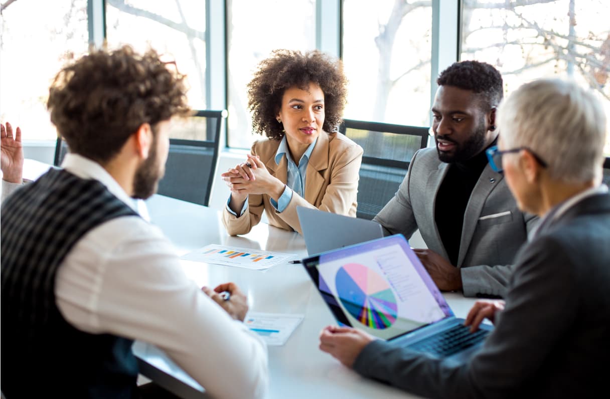 A group of people sitting at a table looking at graphs.