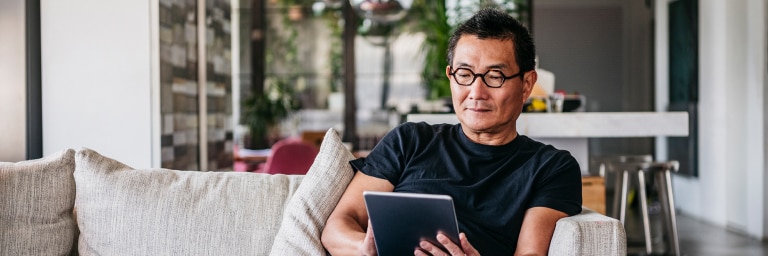 An investor looks at his tablet while seated on his couch